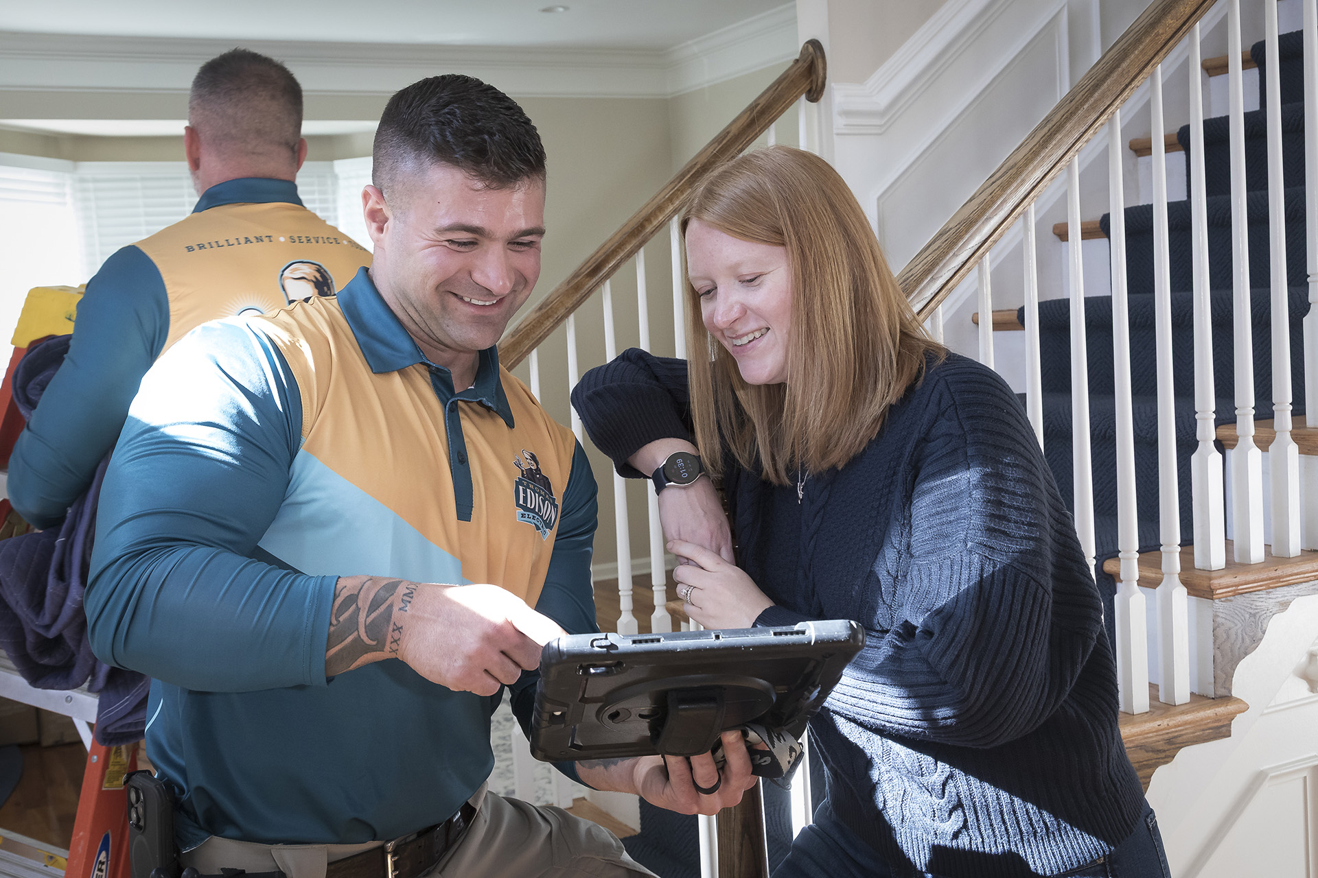 Electrician showing a customer project details on a tablet.