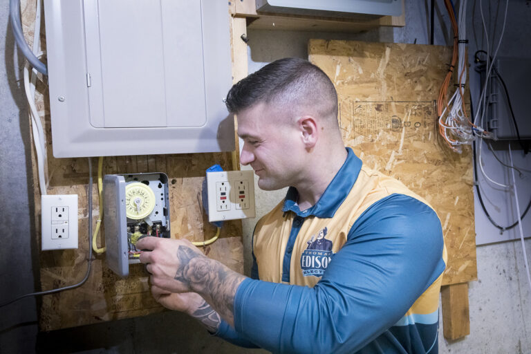 Electrician adjusting a mechanical timer near a home’s electrical panel.