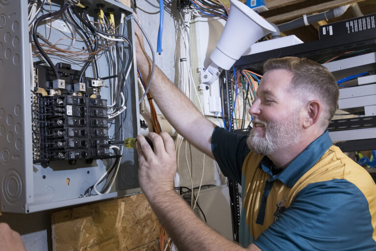 Electrician tightening connections inside a home electrical panel.