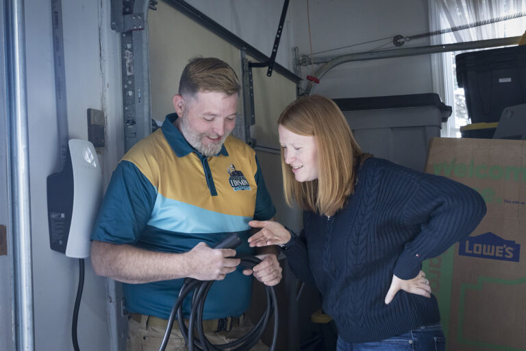 Electrician explaining Tesla EV charger setup to a homeowner.
