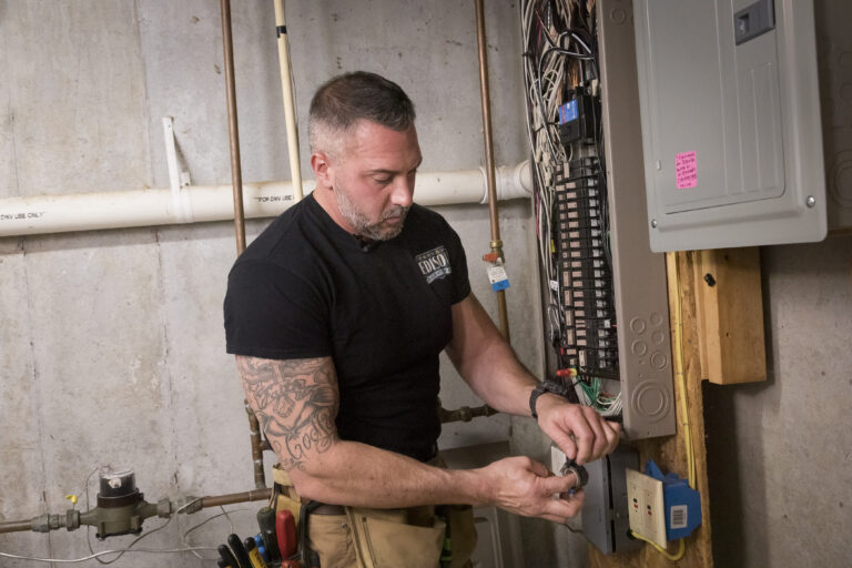 Electrician inspecting and wiring a home’s main electrical panel.