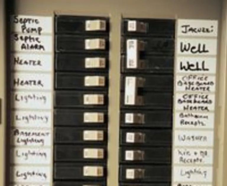 The image shows a residential electrical circuit breaker panel, which is the main distribution point for electricity in a home. It contains branch circuit breakers that trip to cut off power to specific areas or appliances when circuits are overloaded or experience a fault.
