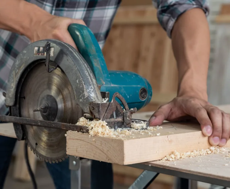 This image shows someone using a circular power saw to cut a piece of wood.