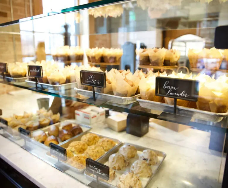 This image shows a display case at a bakery offering a variety of cupcakes, pastries, and other sweet treats.