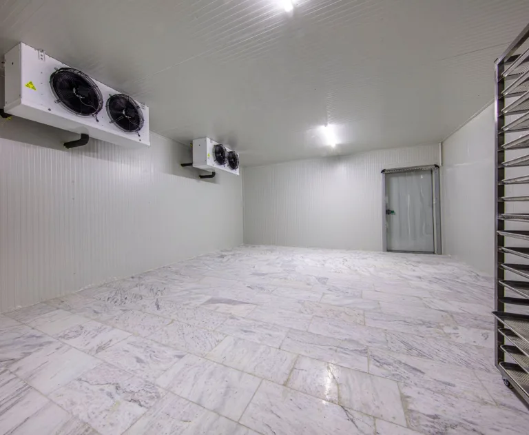 An image of a walk in cooler with white tile floors and white walls.
