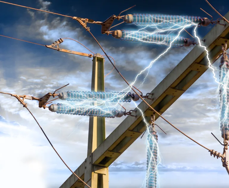 The image depicts high-voltage power transmission lines and insulators experiencing an electrical arc or discharge, likely caused by a fault or insulation failure.