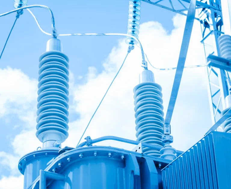 This image features high-voltage equipment, specifically a power transformer with insulator bushings used in electrical substations.