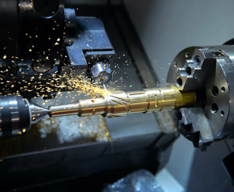 This image shows a CNC turning machine in operation, specifically shaping a brass component.