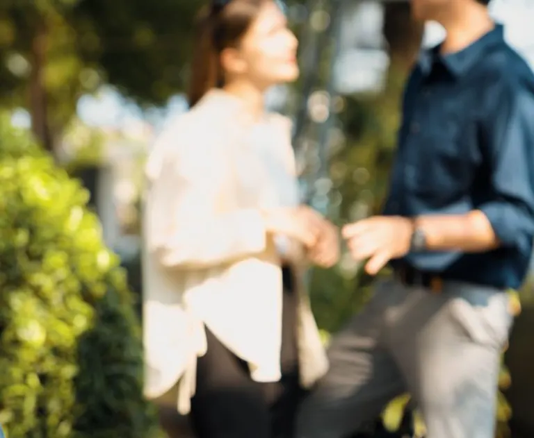 This image shows two individuals standing outdoors in a lush, green environment.
