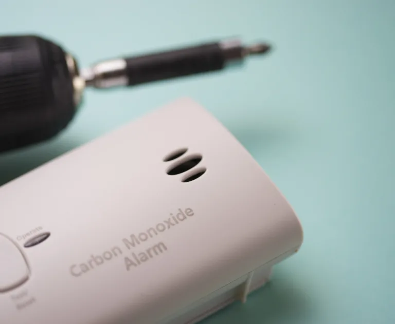 An up-close photo of a carbon monoxide detector on a blue background.