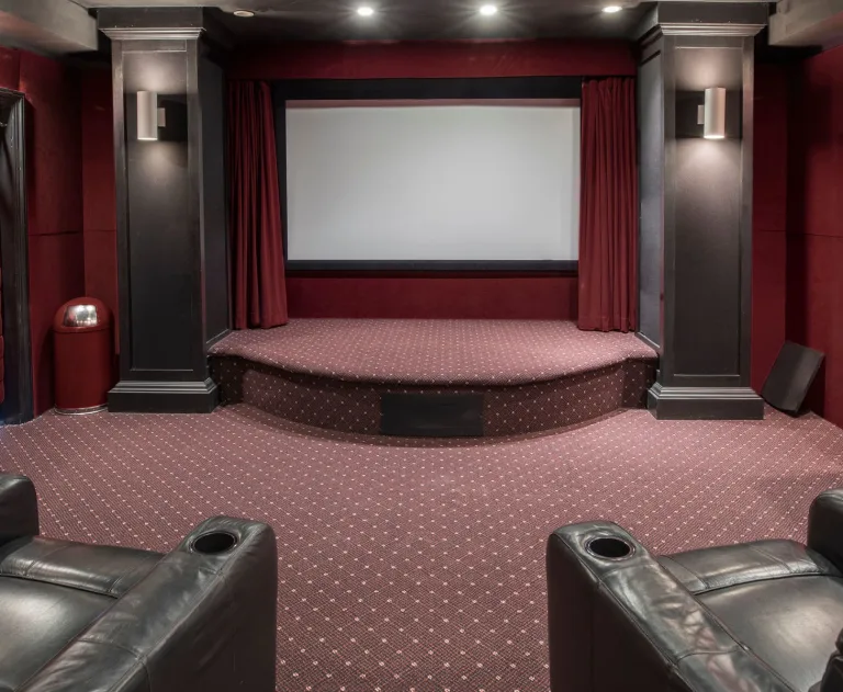 The image displays a custom residential home theater room designed to emulate a commercial cinema experience.