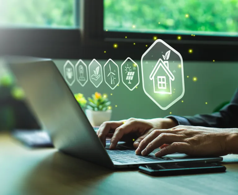This image represents the concept of green technology in the real estate industry, showing a person using a laptop to manage or research sustainable home solutions.