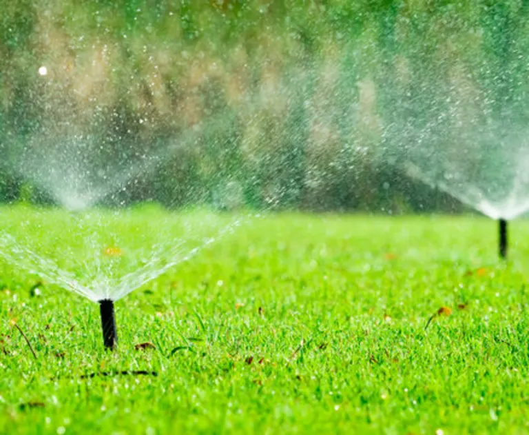 This image shows an automatic lawn sprinkler system watering green grass.