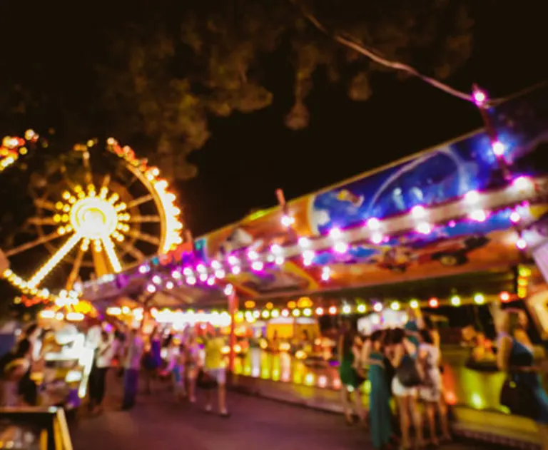 A carnival scene at night, with bright neon lights and a Ferris wheel.