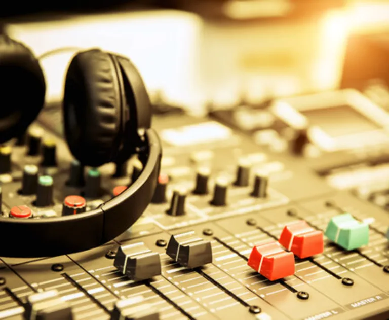 This image features a professional audio mixer with headphones resting on top, commonly used in recording studios and live sound environments.
