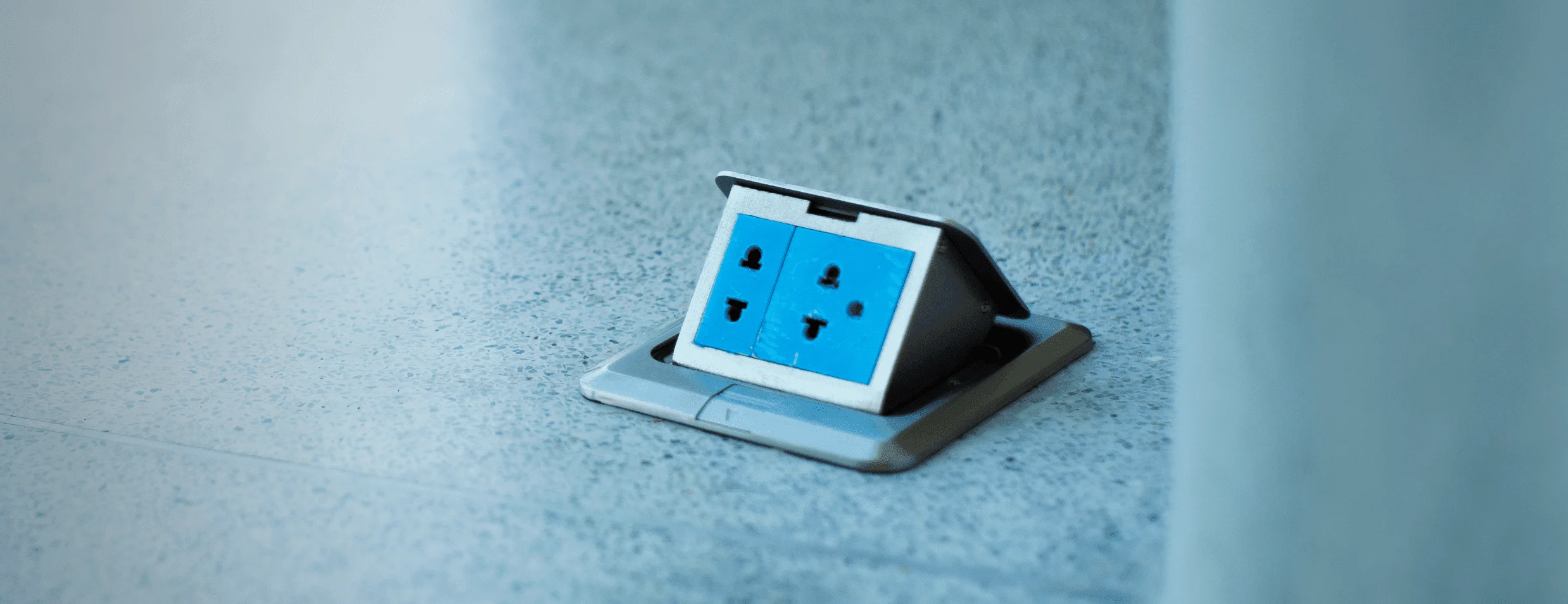 The item pictured is a pop-up floor outlet box, which provides a convenient and concealed electrical solution for modern spaces. These outlets remain hidden beneath the floor surface when not in use to maintain a clean environment.