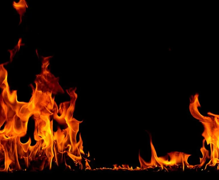 This image is a stock photograph depicting fire flames isolated on a black background. It features orange and yellow flames at the bottom, mimicking a fire line or bonfire effect.