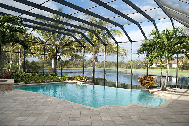 The image features a swimming pool covered by a screen enclosure, commonly referred to as a pool cage or lanai.