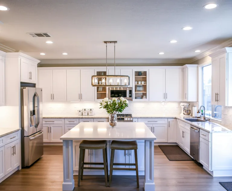 This image features a modern white kitchen with Shaker-style cabinets and engineered stone countertops.