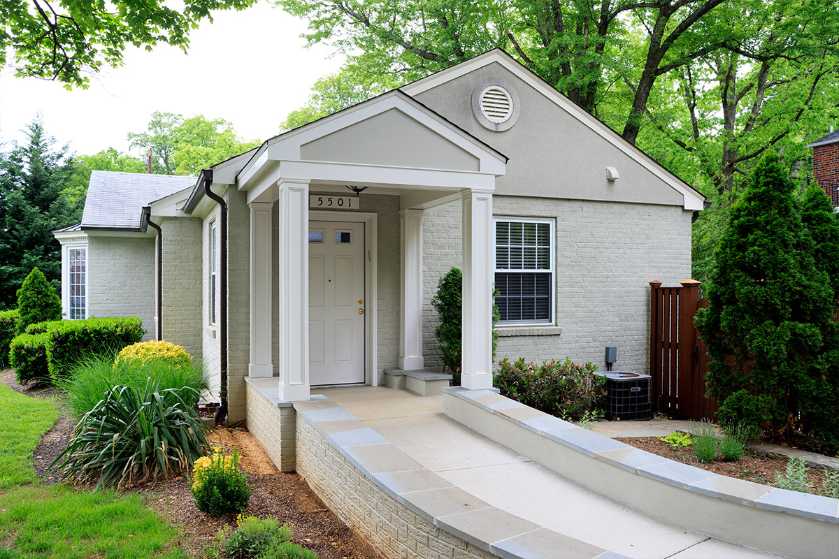 This image features a residential house that has been remodeled to include a wheelchair-accessible ramp leading to the front door.