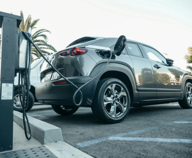 This image features a modern electric vehicle plugged into a public charging station.