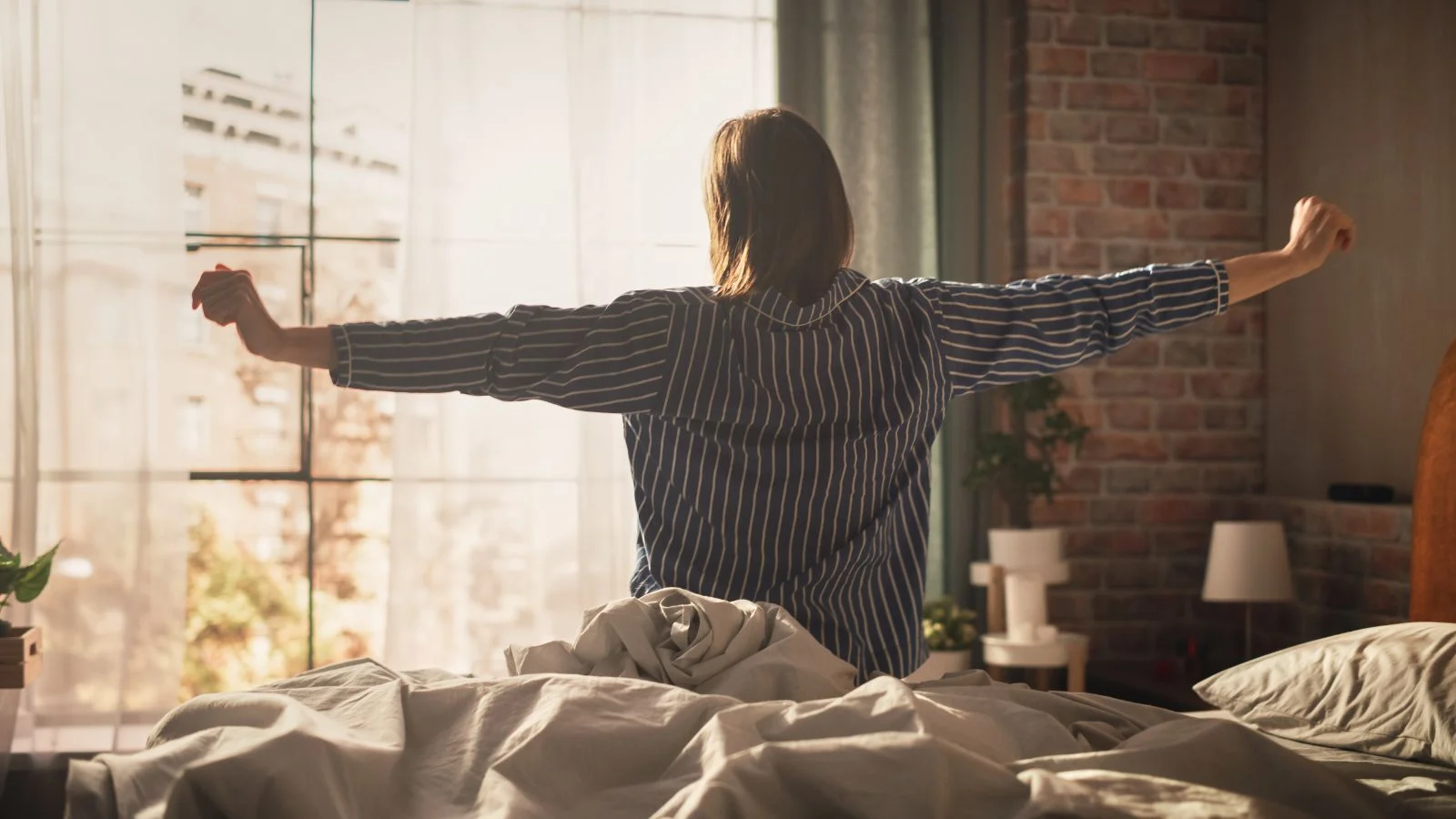 This image shows a person waking up in a sunlit bedroom, suggesting a restful start to the day.