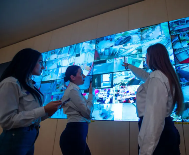 This image shows individuals in a professional security control room monitoring multiple surveillance feeds.