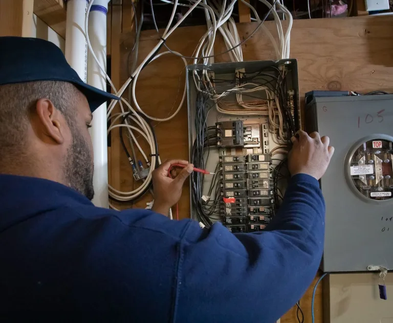 d78c37c7-b8b4-4fce-a112-06b117367fa5_large - Thomas Edison Electric The image shows an electrician near me testing an electrical panel with a multimeter.