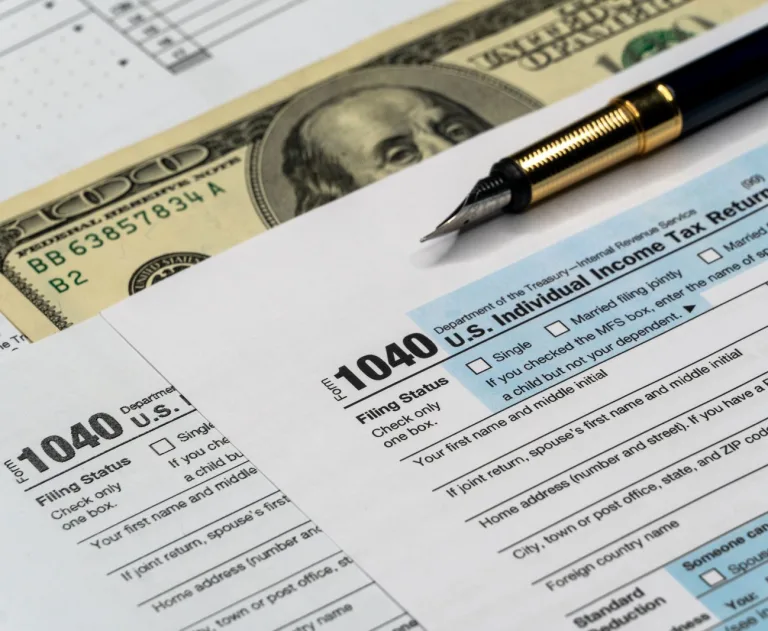 e3322af1-6623-404b-9955-b97f01fed739_large - Thomas Edison Electric The provided image displays a detail close-up of IRS Form 1040 (U.S. Individual Income Tax Return), accompanied by a luxury fountain pen and United States hundred-dollar currency.