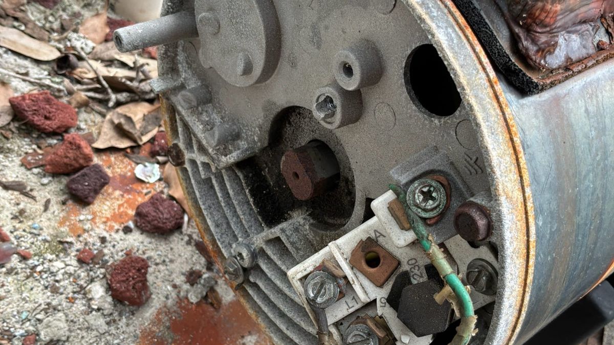 Green bonding conductor landed on a pool pump motor bonding lug, Treasure Coast - Thomas Edison Electric Green solid copper bonding conductor landed on the bonding lug of a corroded pool pump motor at a Treasure Coast equipment pad