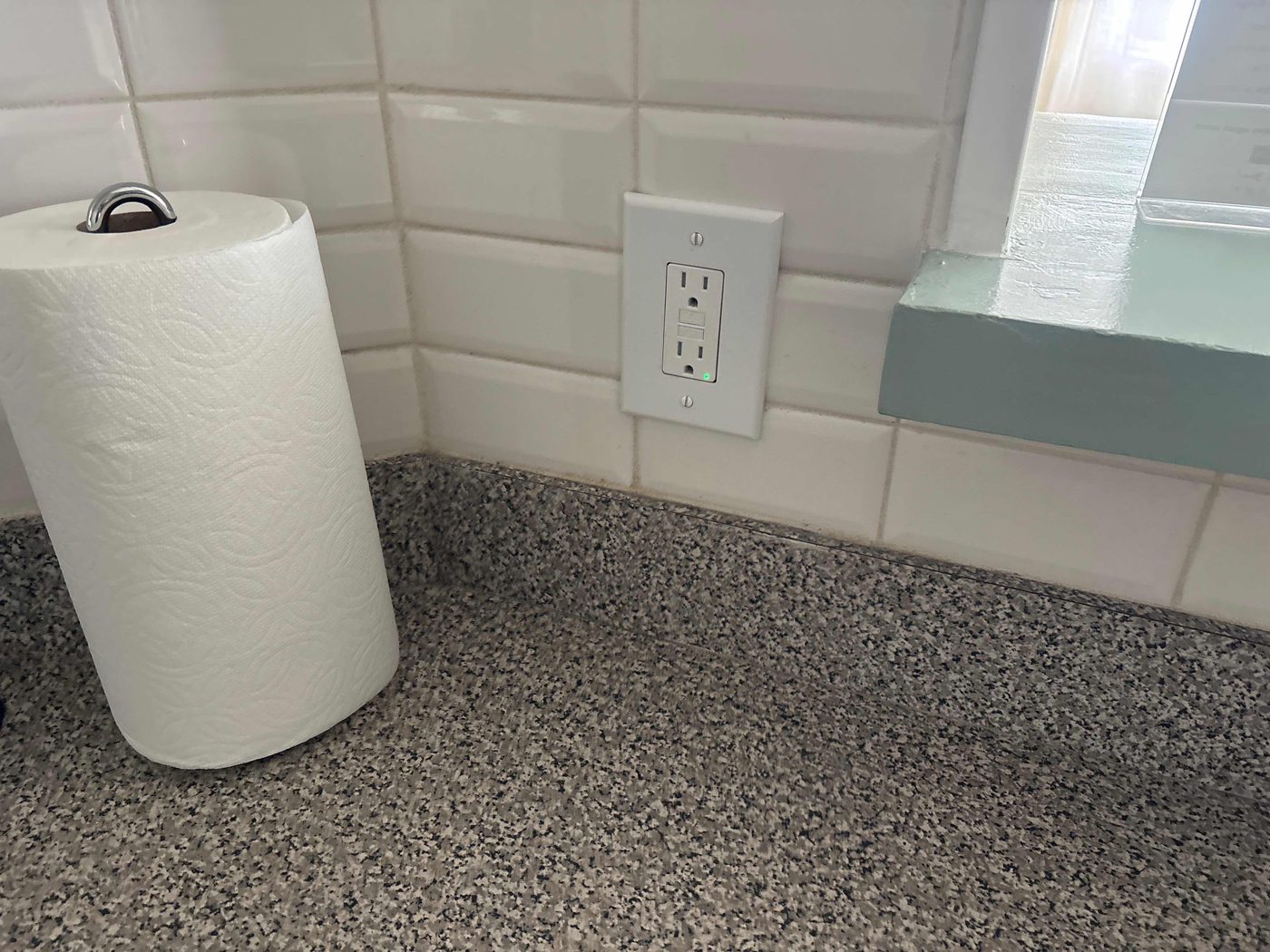 GFCI protected kitchen outlet on a white tile backsplash