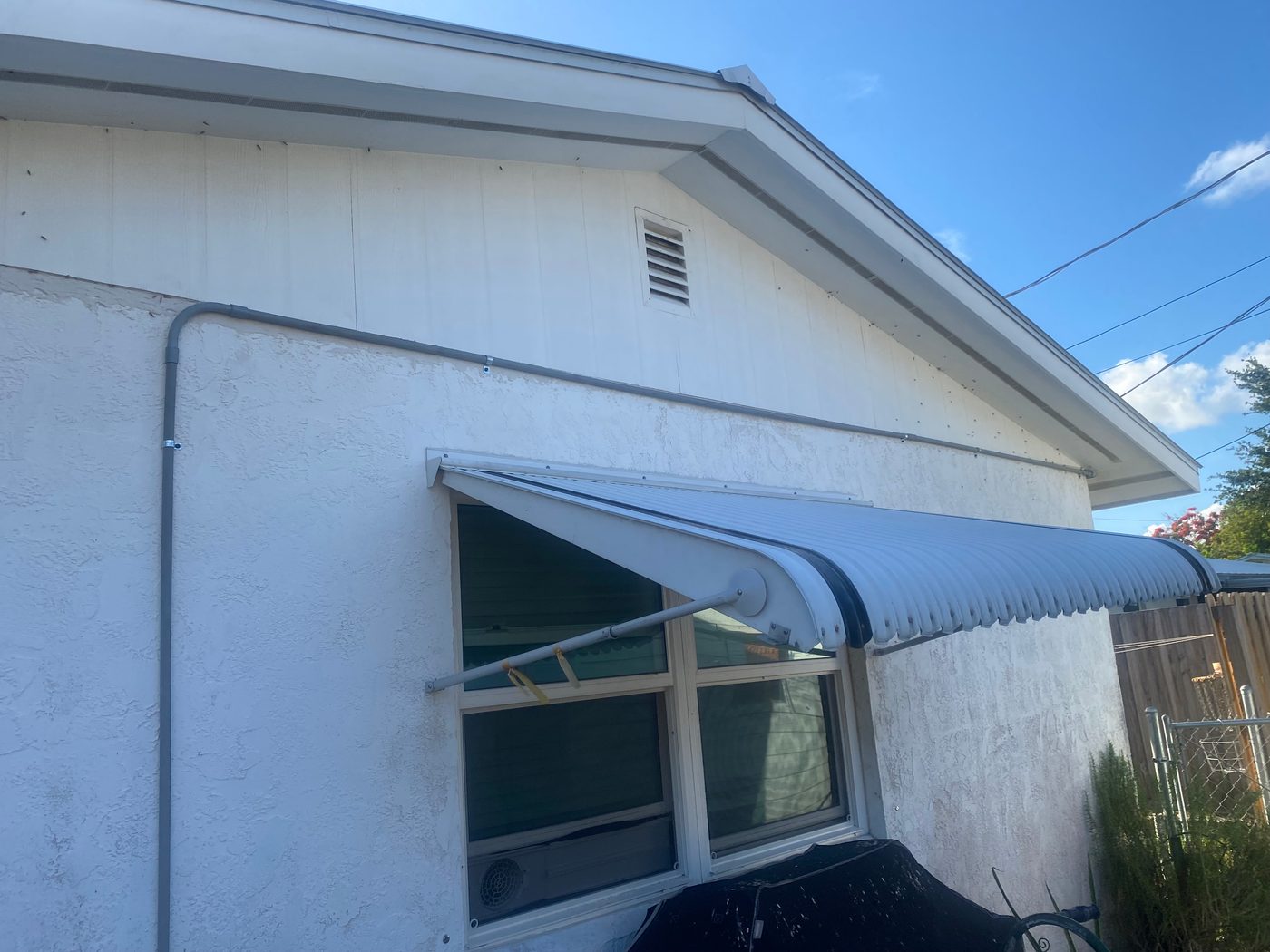 Exterior electrical conduit on a Florida home under a clear sky