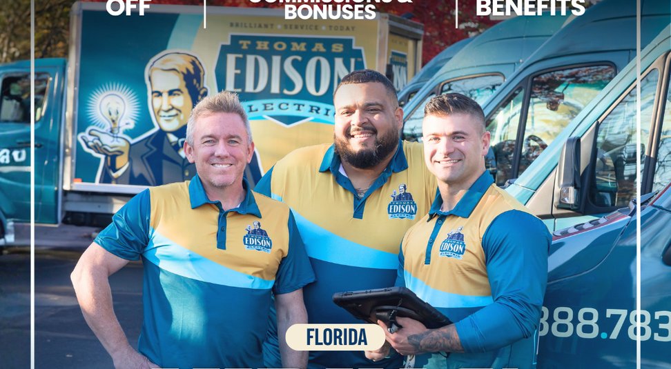 tee-team-florida - Thomas Edison Electric Three Edison Electric technicians in blue-and-gold polo shirts pose smiling in front of service vans, one holding a tablet; Florida